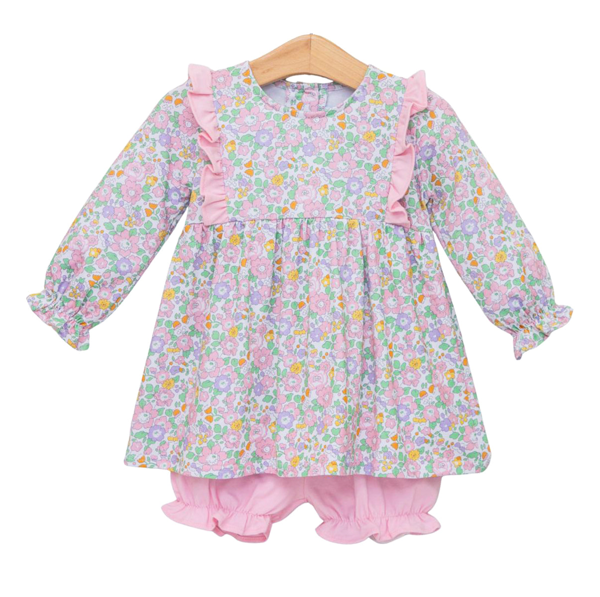 A toddler girl's long-sleeve tunic top  and bloomers set hanging on a wooden hanger against a white background. The dress features a light pink and lavender floral print with pink ruffle trim, while the bloomers are solid light pink.