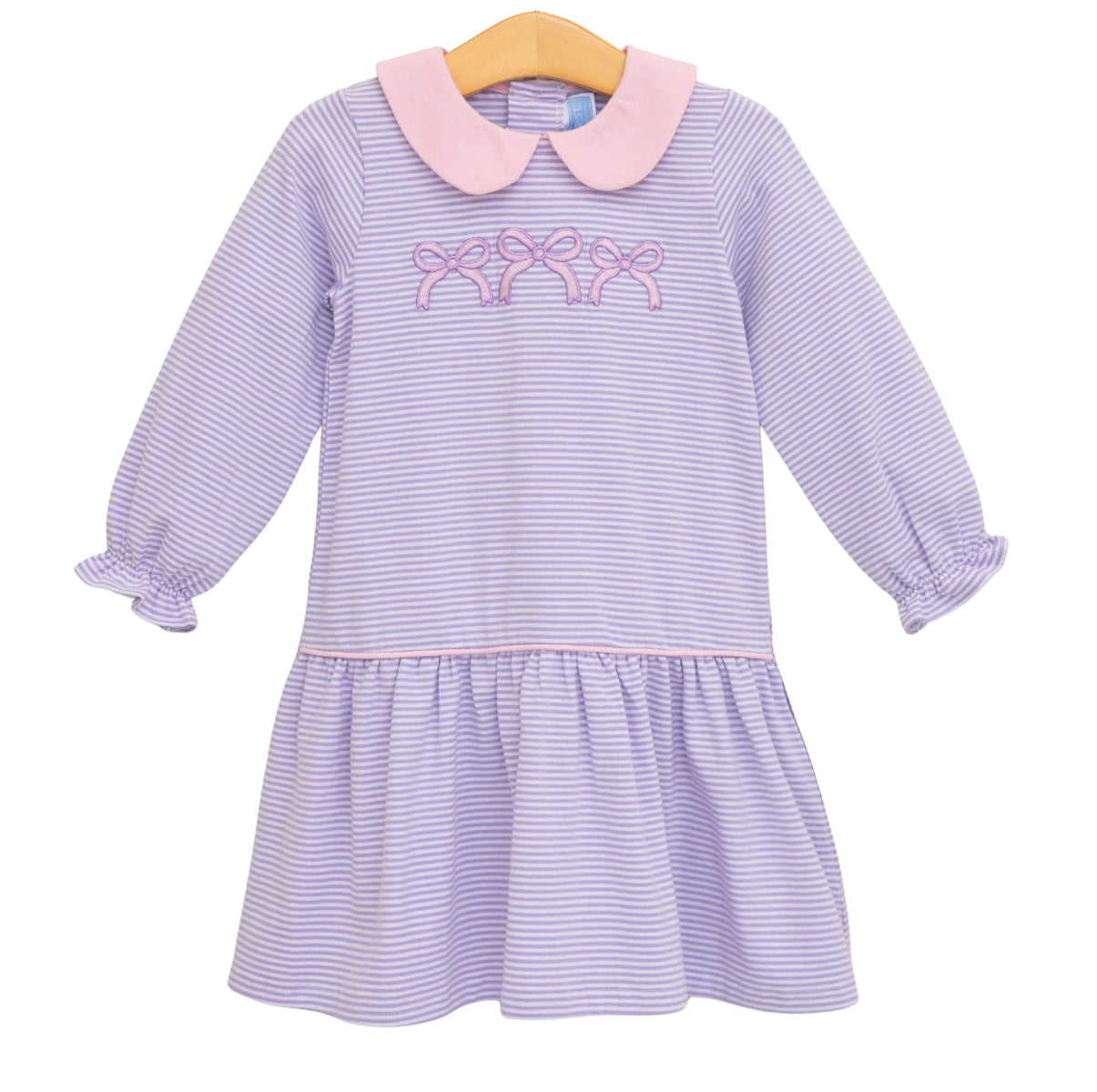 A toddler girl's long-sleeve dropwaist dress with lavender and white horizontal stripes, a light pink Peter Pan collar, and matching pink embroidered bows on the chest. 