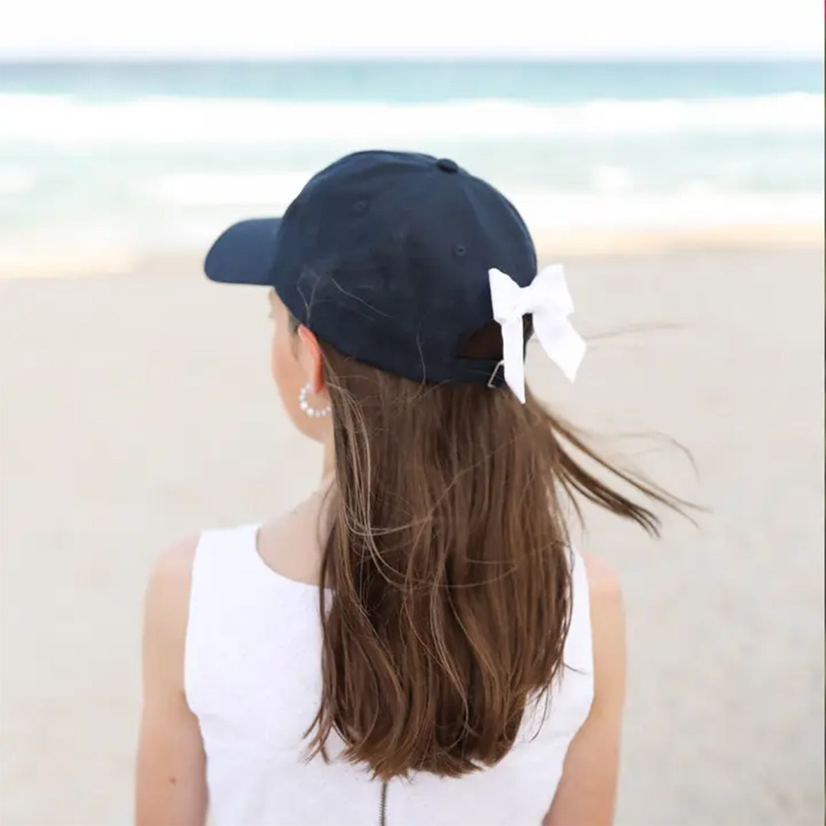 Navy blue girls baseball hat with a white bow on the back and USA embroidery on the front