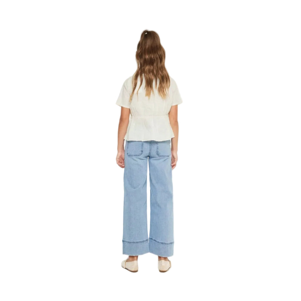 Person wearing a white top and light blue jeans on a white background