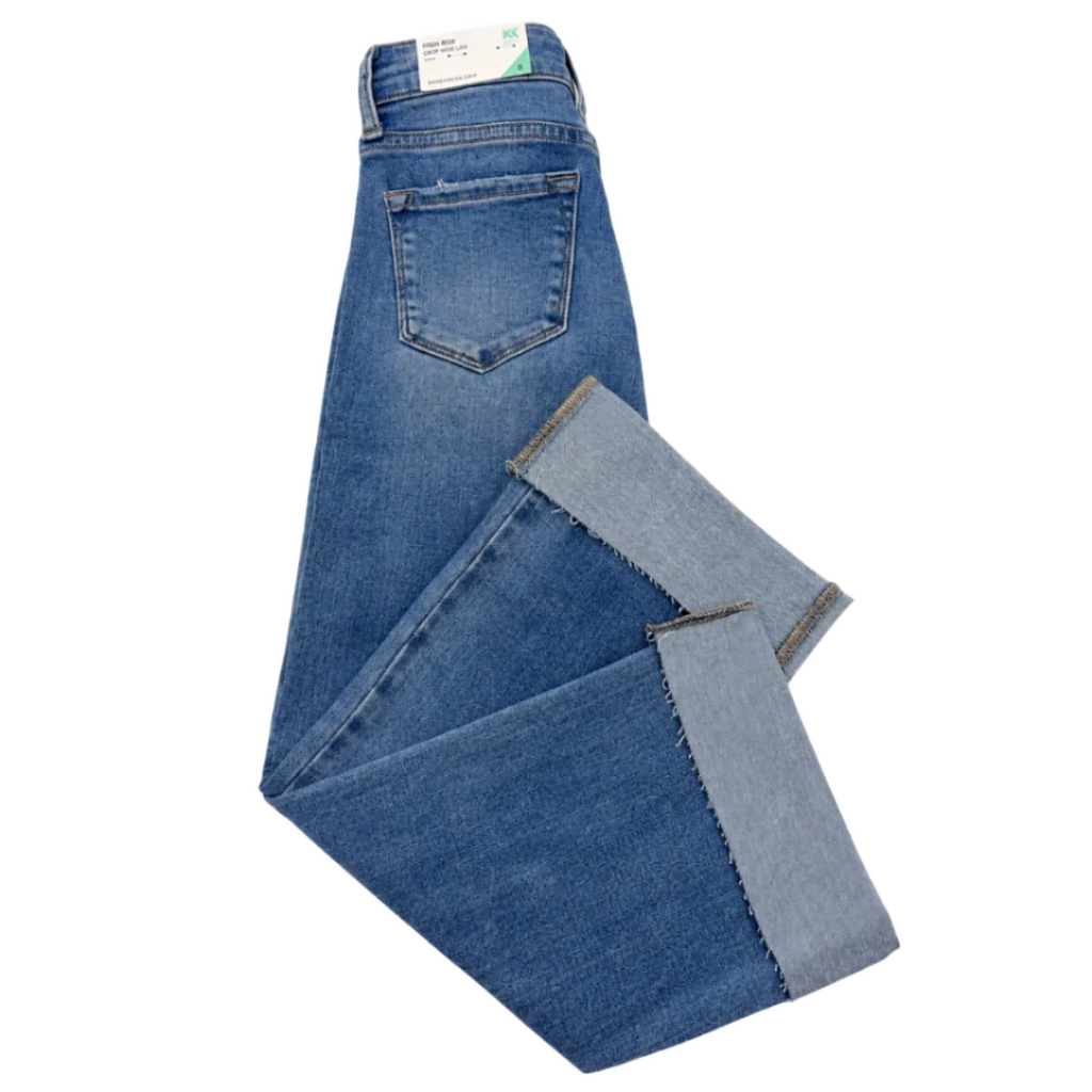 A pair of folded blue denim jeans with rolled cuffs showing a lighter inner denim lining, photographed on a plain white background.