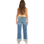 Woman wearing blue jeans and a colorful top on a white background