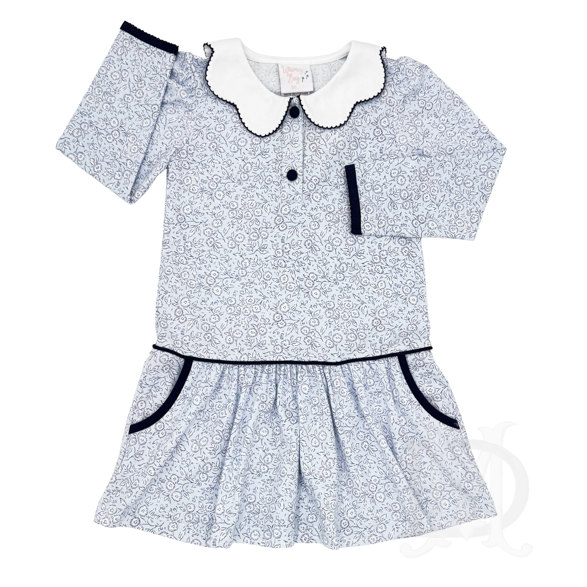 A toddler girl's long-sleeve dress featuring a blue and white floral pattern, a white scalloped collar with navy trim, a button placket, and navy trim.